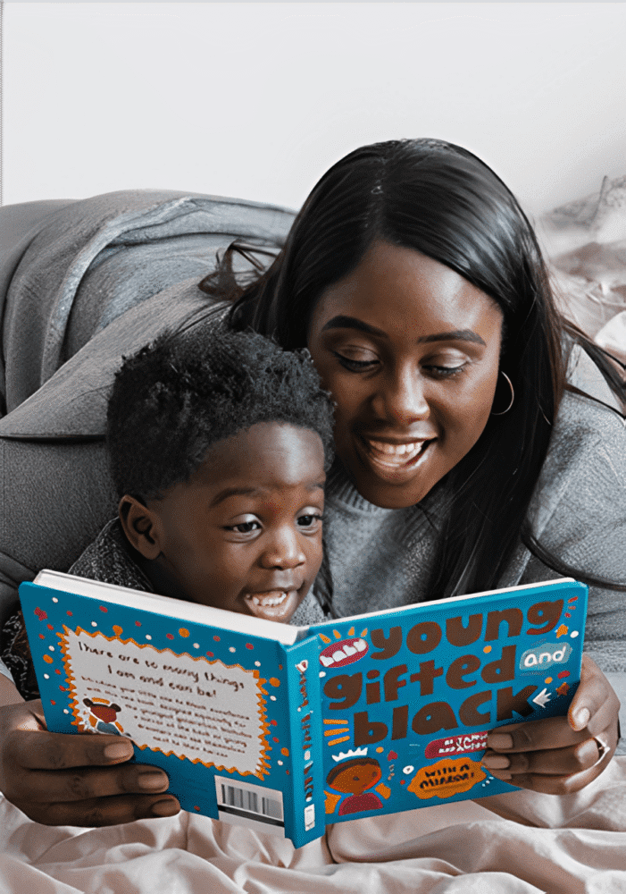 A woman and child lie on a bed, joyfully reading the book "Young, Gifted and Black."